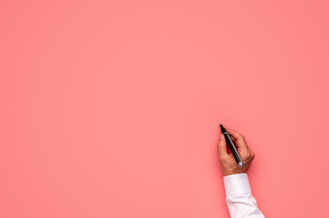 Male hand about to write on a blank pink background
