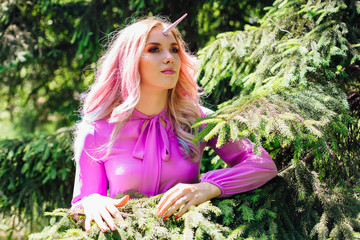 Fairy girl unicorn with pink hair in summer forest