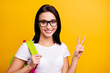 Close up photo amazing she her lady hold arm hand school colored study modern cool backpack v-sign symbol say hi positive friendly wear specs casual white t-shirt isolated bright yellow background