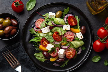 salad with tomato, cucumber, bel pepper , olives and feta cheese on black plate