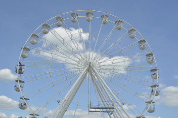 White ferris wheel of the amusement park in the blue sky background.