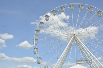 White ferris wheel of the amusement park in the blue sky background.