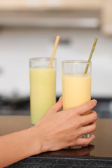 Female hand taking glass of banana smoothie with straw