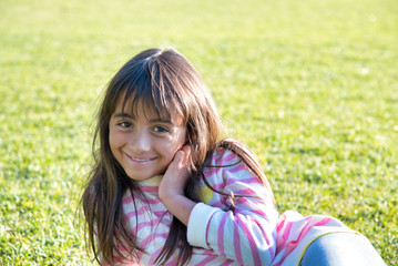 Young girl happy smiling lying on a park grass