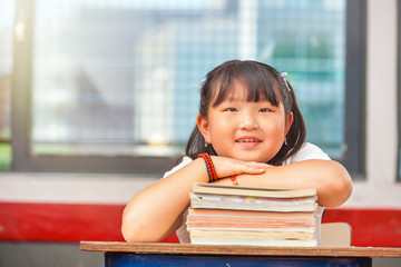Asian young girl touching her books in school classroom