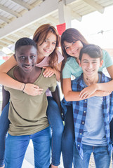 Obraz premium Schoolmates piggybacking and relaxing in school hallway