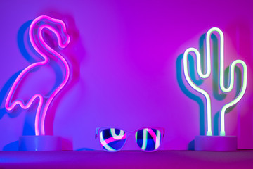 Hello summer with flamingo,cactus,sunglasses refection neon pink and blue and green light on table with copy space.Trendy vacation holiday background. © weedezign