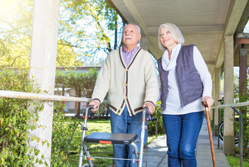 Senior retired couple in the garden with walker and stick