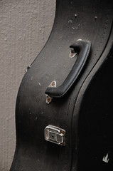 Close up of an old guitar case against a wall