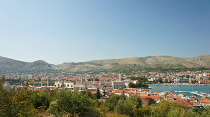 Scenic top view of the city with mountain background, beautiful cityscape with houses, sunny day, Trogir, Dalmatia, Croatia