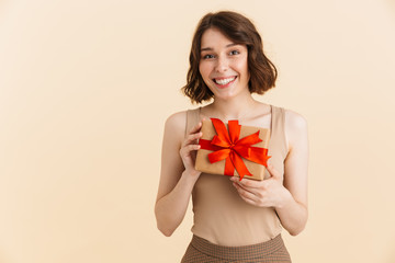 Portrait of gorgeous caucasian woman 20s dressed in casual clothes smiling at camera while holding present box