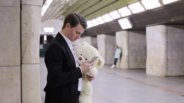 Man calls his sweetheart on the phone, in his hands a gift is a bear toy.