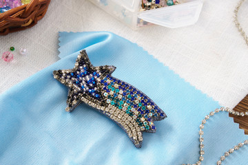 Brooch star comet handmade beaded  on the table on blue background