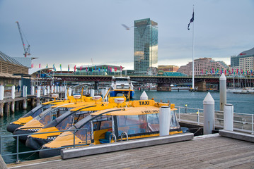 Obraz premium SYDNEY - AUGUST 18, 2018: Water Taxis in Darling Harbor on a beautiful day. Sydney attracts 20 million tourists annually