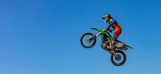 Biker does the trick and jumps in the air. Extreme concept, adrenaline. Copy space. Sky background