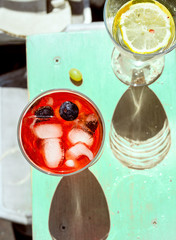 Glasses of aperol spritz and white wine with ice and fruits on light green colored bar counter...