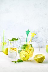 Homemade lemon and mint lemonade in glass jars and bottles on white background