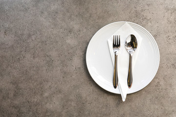 Fork plate spoon and napkin on stone  table