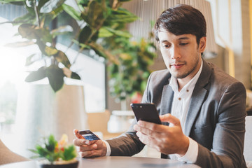 Asian businessman using credit card and mobile phone for online financial payment and shopping