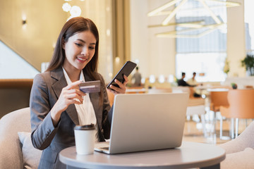 Asian businesswoman using credit card and mobile phone for online financial payment and shopping