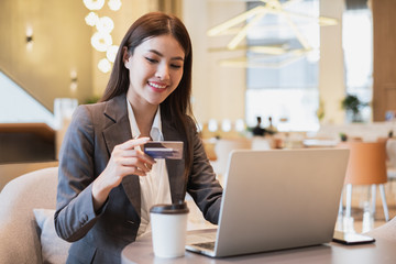 Asian businesswoman using credit card and mobile phone for online financial payment and shopping