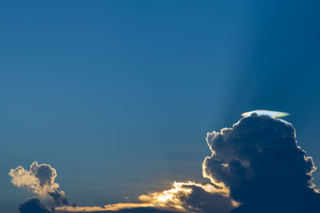 Cloud iridescence on blue sky with sunbeam.