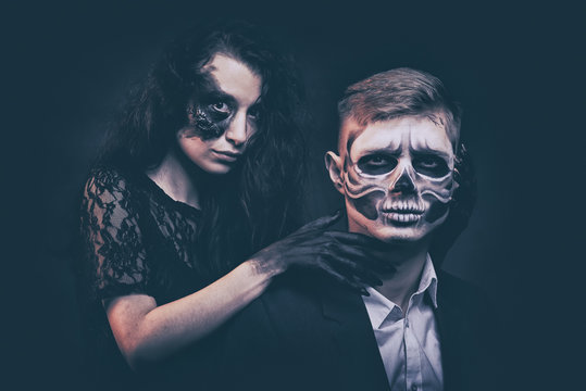 a young succubus girl with a feathered skeleton on a smoke background with hands stained with soot and a burned face with an expressive look and a pleasant appearance in a black dress