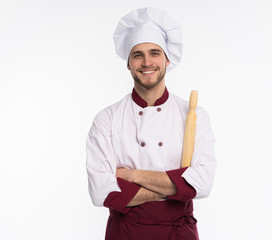 Portrait of positive toothy chef cook in beret, white outfit having tools in crossed arms looking at camera isolated on white background.