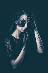 a young succubus girl on a smoke background with hands stained with soot and a burned face with an...