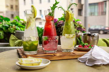 Summer soft drinks, a set of lemonades. Lemonades in jugs on the table, the ingredients of which they are made are arranged around.