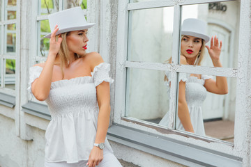 Sexy modern bride in white cylinder hat watching in to mirror window