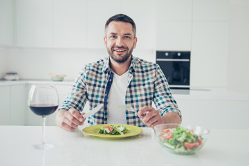 Fototapeta na wymiar Portrait of charming imposing mature guy sit table hold hand fork knife want cut pleasant evening cheerful checked shirt big light apartment wineglass