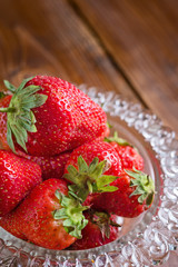 ripe strawberry in glass bowl at wooden table. macro. flat lay