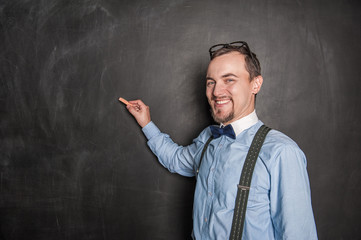 Happy smiling teacher with chalk on blackboard background