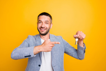 Portrait of his he nice-looking attractive cheerful positive guy holding in hand pointing at keys...