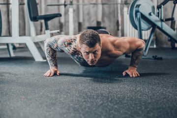 bodybuilder makes push-ups in the fitness room . photo with copy space
