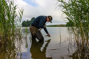 Angler catching the fish in the lake. Catch and release practice within recreational fishing