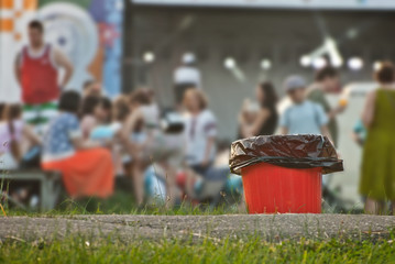 Red litter on green grass. Garbage in the nature after the concert.