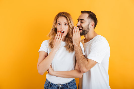 Image Of Surprised Couple Man And Woman In Basic T-shirts Whispering Secrets Or Gossips To Each Other