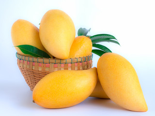 ripe mangos and leaves in a basket on a white background