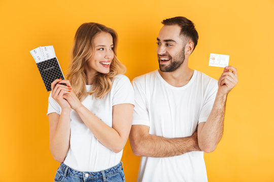 Image of beautiful couple rejoicing while holding credit card and passport with travel tickets