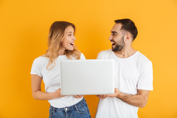 Image of pretty couple man and woman rejoicing while holding laptop together
