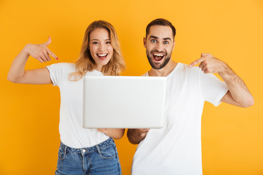 Image of excited couple man and woman rejoicing together while pointing fingers at laptop