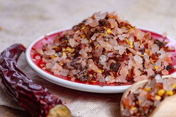 Gross sea salt mixed with dried red hot chili pepper, colorful seasoning close-up