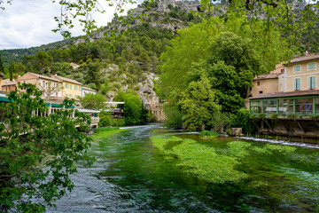 Fototapeta na wymiar South of France, view on small Provencal town of poet Petrarch Fontaine-de-vaucluse with emerald green waters of Sorgue river