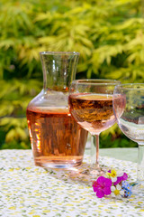 Wine carafe and glasses with cold rose wine and wild flowers in summer sunny day