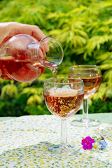 Wine carafe and glasses with cold rose wine and wild flowers in summer sunny day