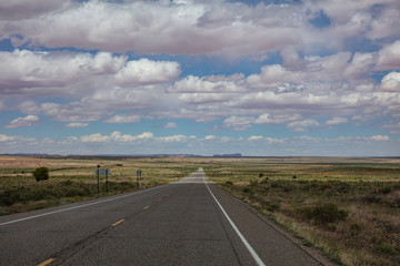 Fototapeta na wymiar Long highway, cloudy blue sky. Monument Valley Navajo nation, Arizona-Utah USA