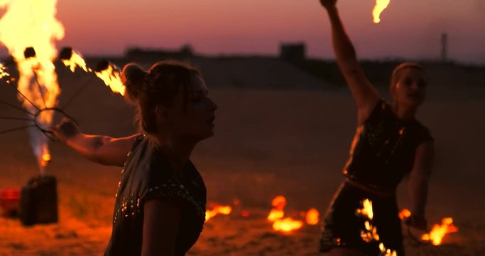 Professional dancers women make a fire show and pyrotechnic performance at the festival with burning sparkling torches.