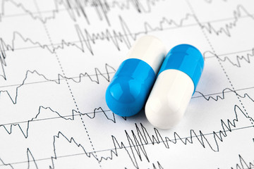 Close-up photo of white and blue pills on EKG graph